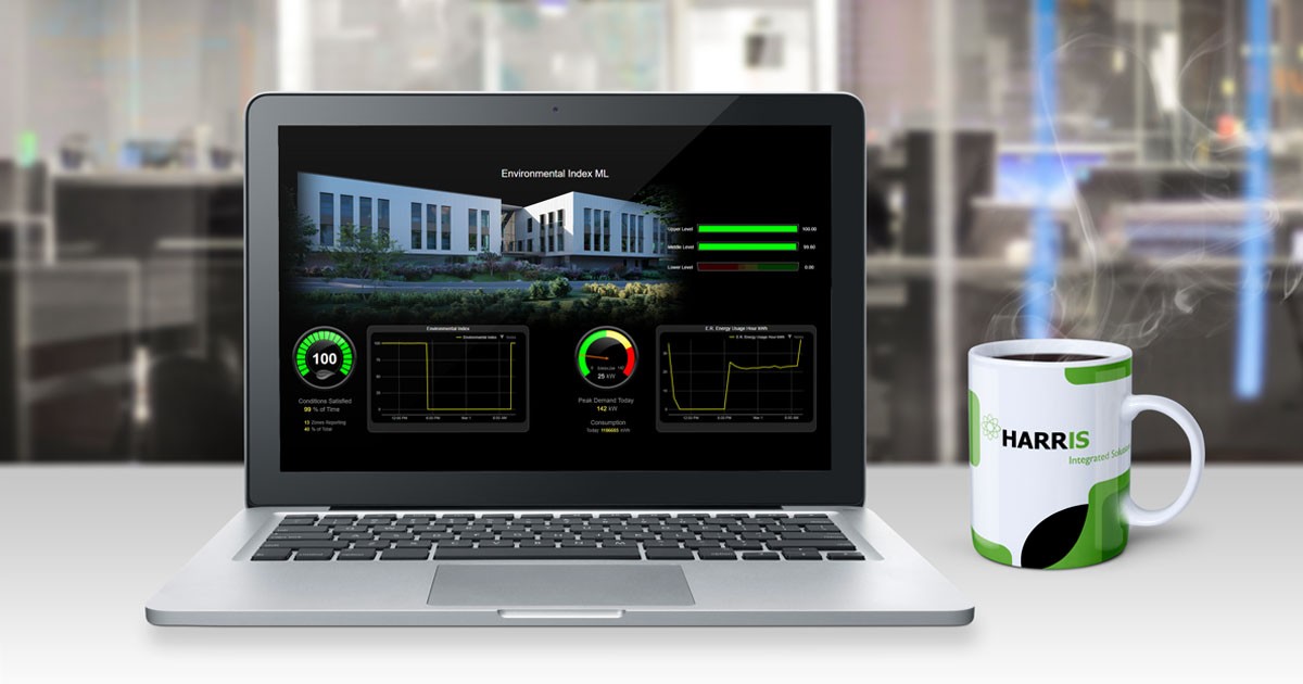 Computer on desk showing a building management system with a cup of hot coffee with the Harris Integrated Solutions logo next to it.