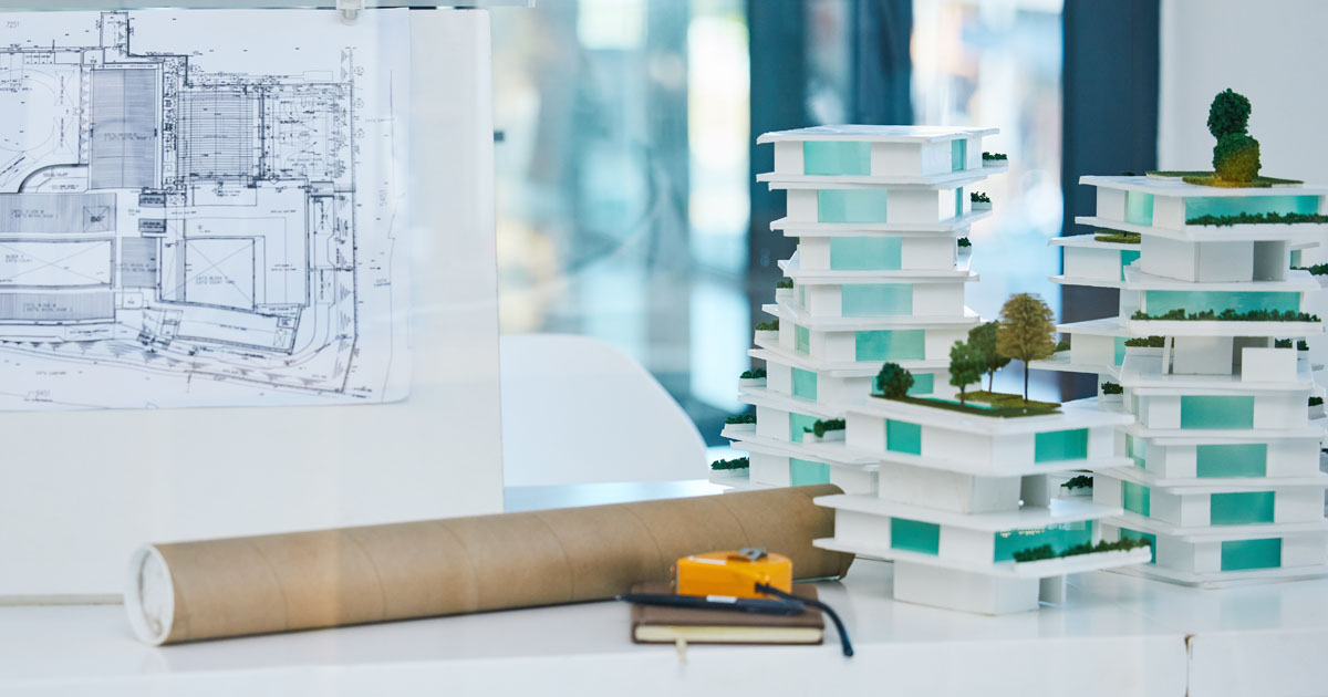 Building blueprint and scaled buildings on a desk.