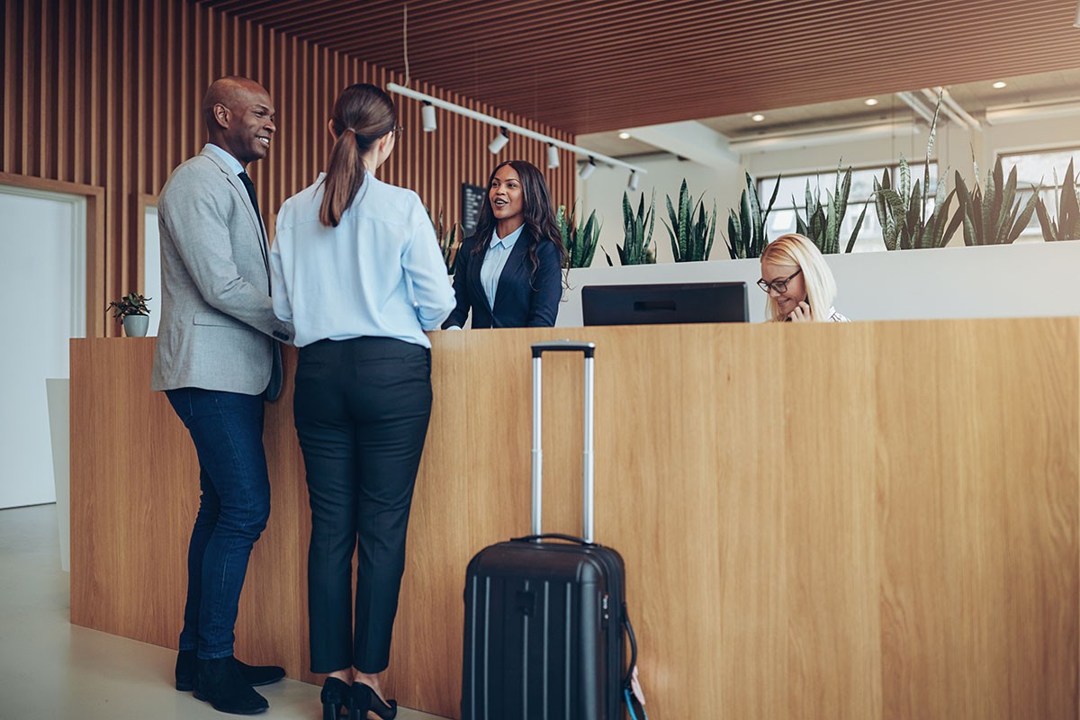 Two smiling guests checking in at a hotel equipped with a building management system